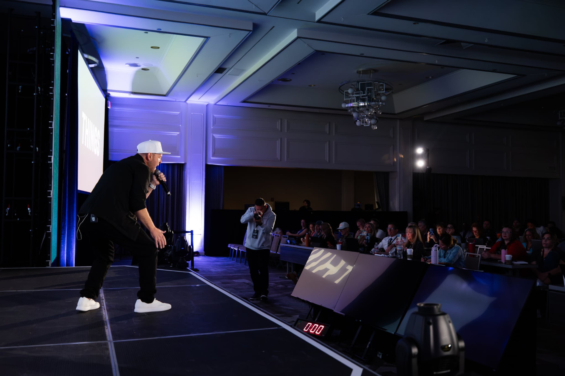 Michael King Jr. leaning toward the audience mid-performance while a photographer captures the moment
